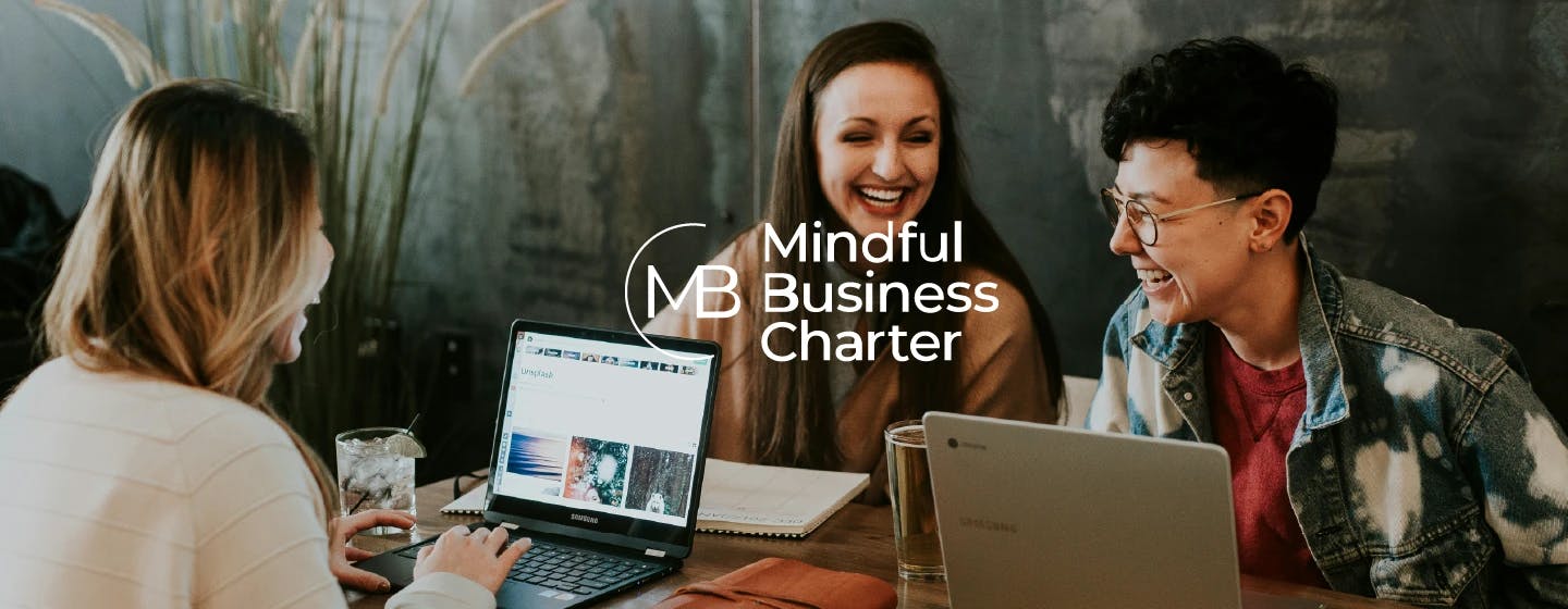 happy people in an office overlaid with the mindful business charter logo